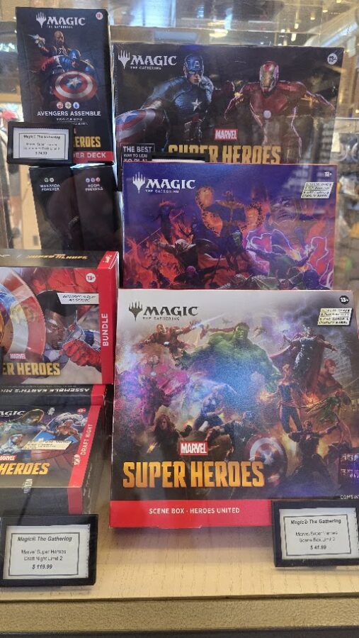 Display of Magic The Gathering Super Heroes boxed sets with Marvel branding on a store shelf featuring Captain America and Iron Man imagery and vivid hero artwork