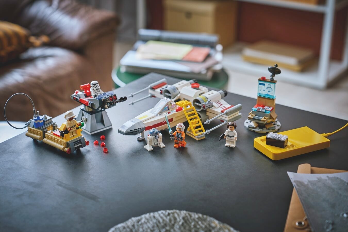 LEGO Star Wars setup on a coffee table with minifigs a white X wing like ship and buildable gear