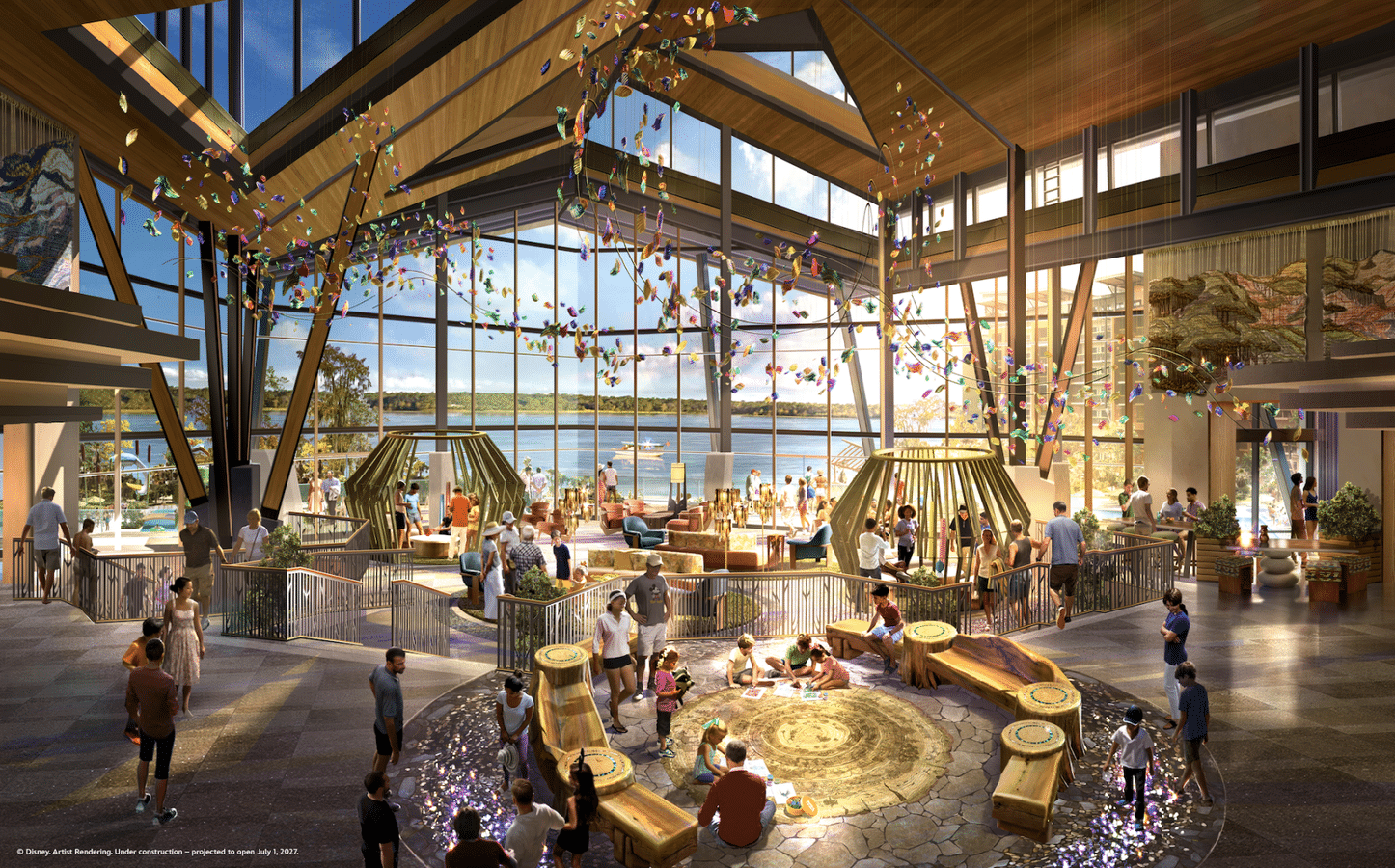 Bright atrium with glass walls overlooking water colorful hanging ornaments and people gathered around a circular stone seating area