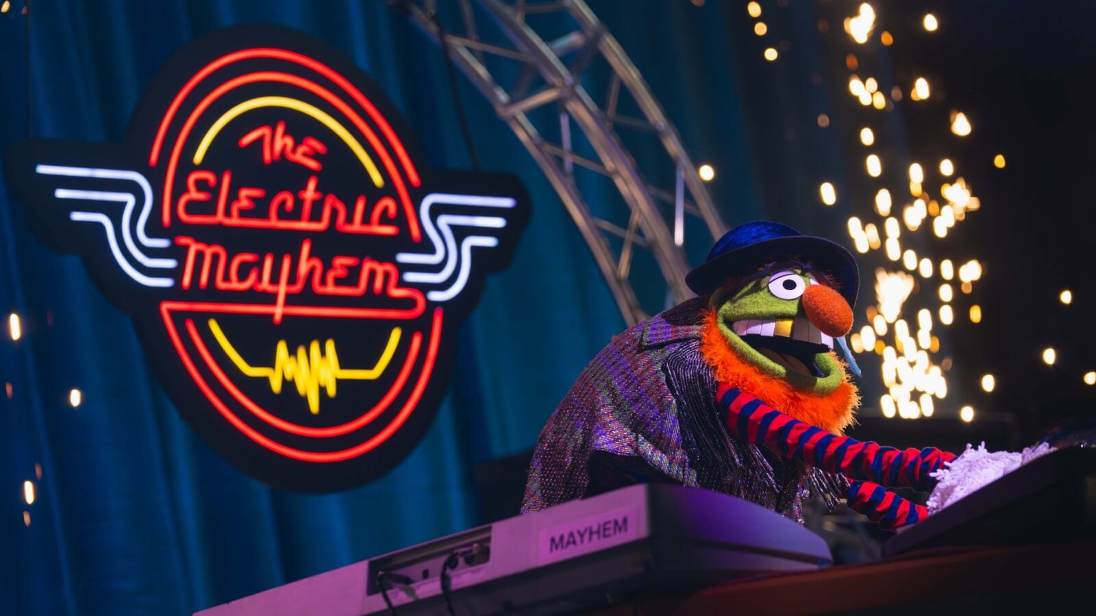 66994202613821447172756806144457151192186312n Fantasy Land News Green Muppet with orange nose and blue hat plays keyboard on stage as neon The Electric Mayhem sign glows behind him