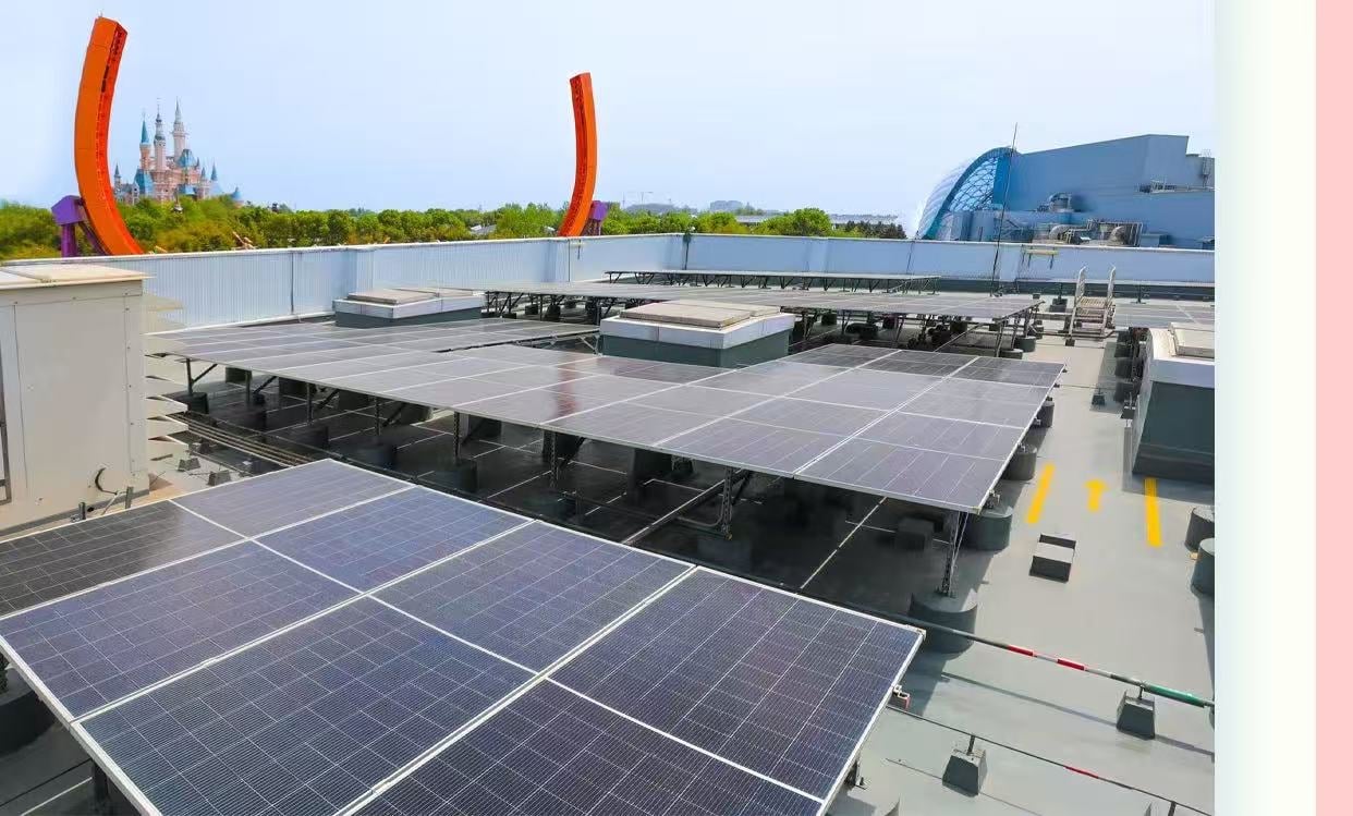 Rooftop solar panels arranged in rows on a building with distant castle like towers and orange arches in the background