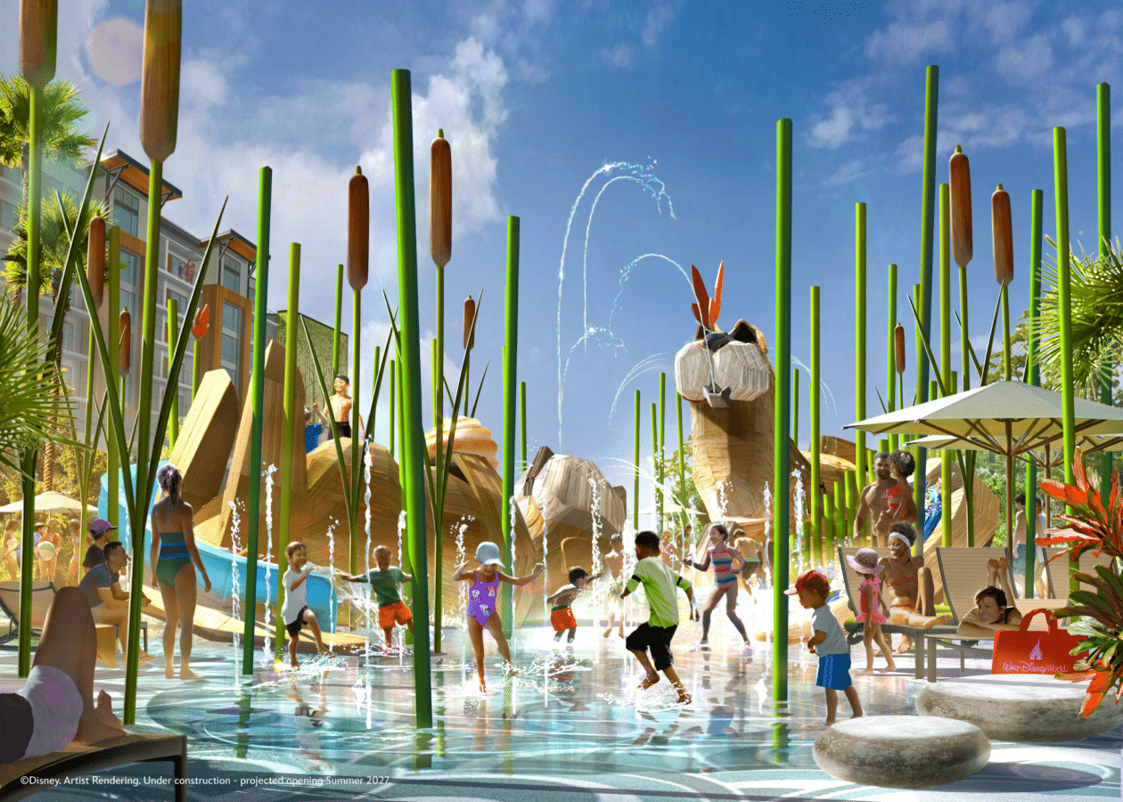 Busy water park scene with tall green reed like structures water sprays and people playing in shallow pools and slides on a sunny day