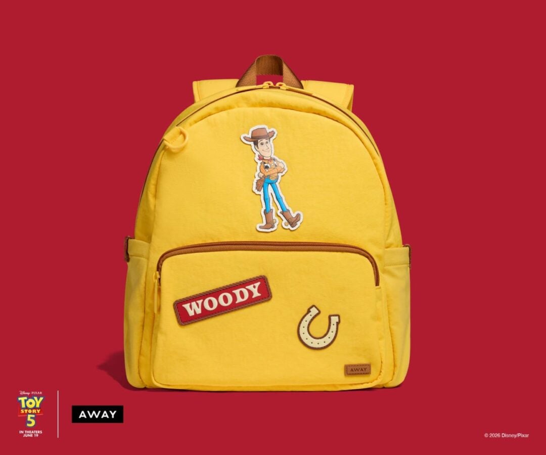 Bright yellow backpack decorated with Woody from Toy Story stickers cowboy figure WOODY patch and horseshoe against a red background
