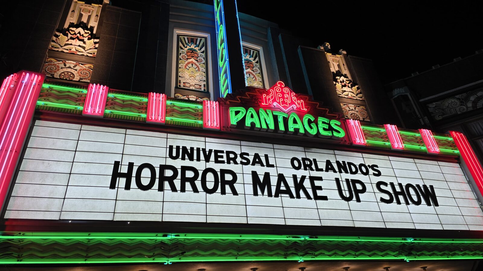 Neon theater marquee reading PANTAGES with bold black text marquee below advertising UNIVERSAL ORLANDOS HORROR MAKE UP SHOW at night