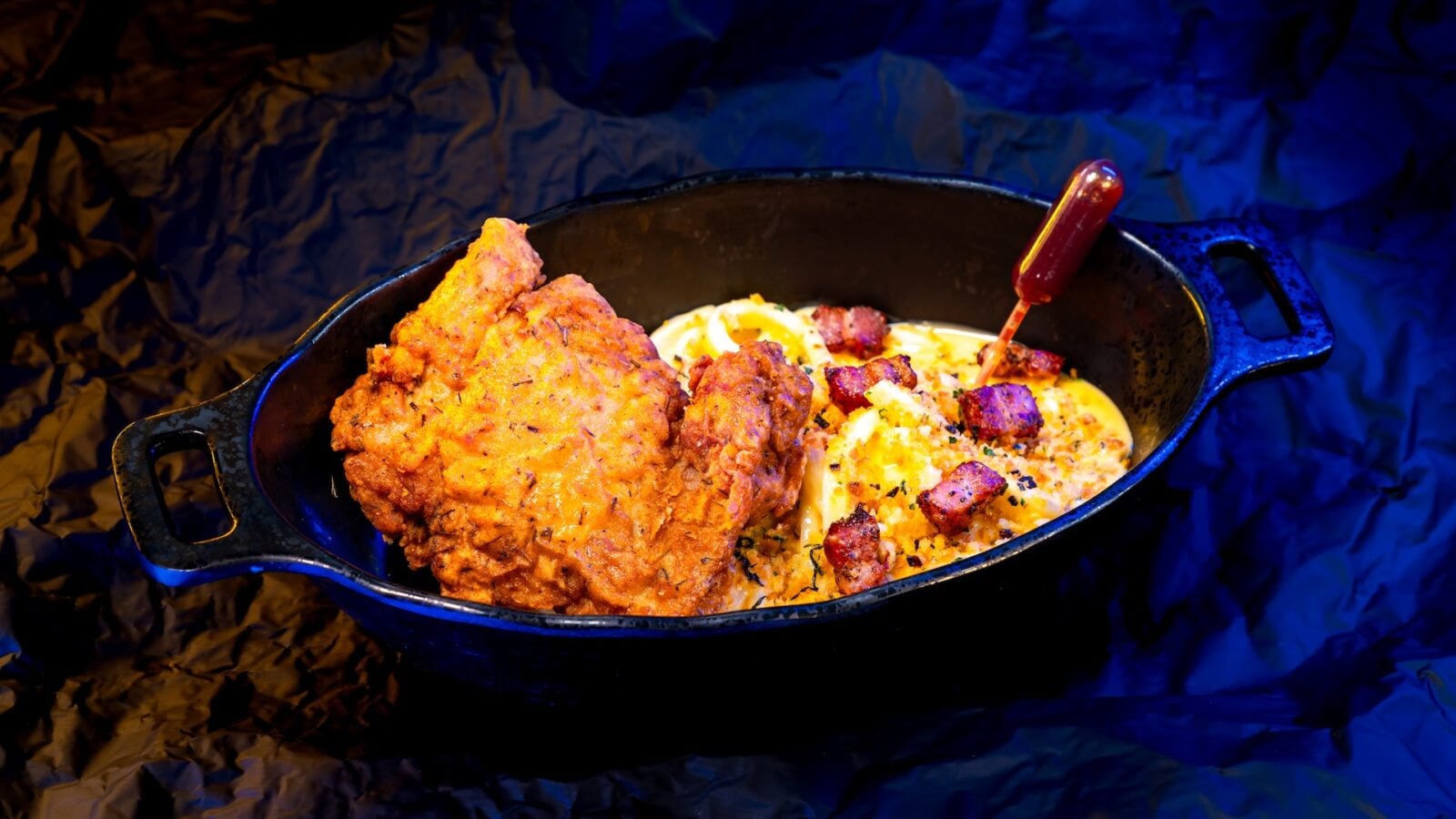 Cast iron skillet with crispy fried chicken and creamy macaroni and cheese topped with bacon bits