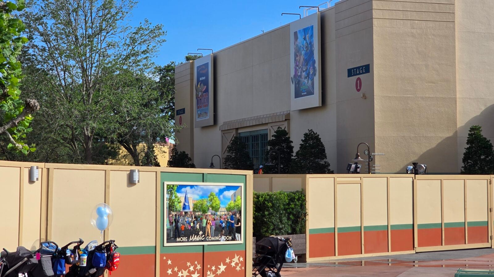 20260514090421 Fantasy Land News Front view of a beige venue with large poster banners stage sign blue sky and surrounding trees in the background