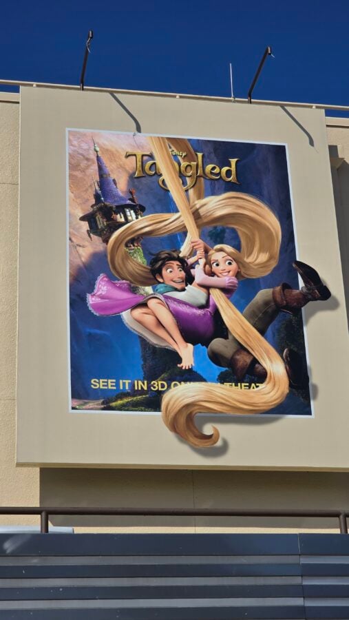 20260514095015 Fantasy Land News Poster ad for Disneys Tangled with Rapunzel and Flynn swinging on long hair castle backdrop promo text reads See it in 3D at the bottom