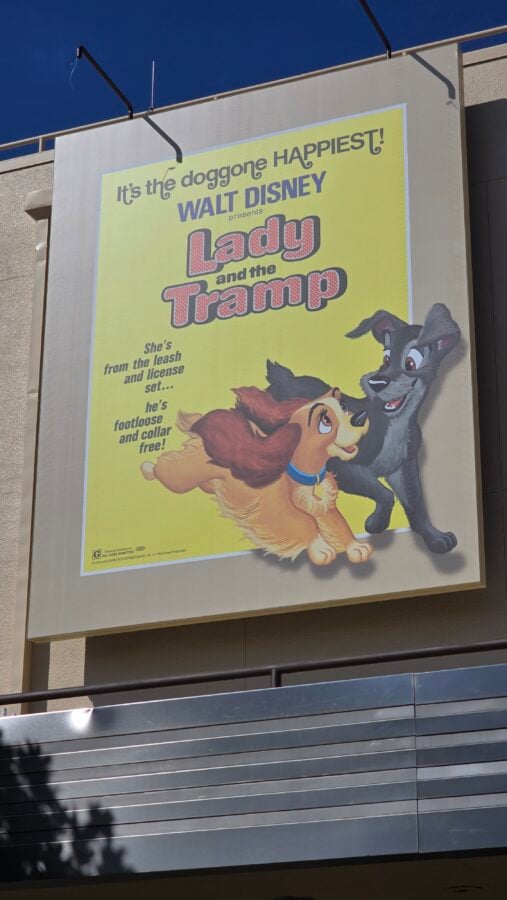 20260514095020 Fantasy Land News Bright yellow poster advertising Walt Disneys Lady and the Tramp with two cartoon dogs leaping together and the slogan Its the doggone happiest