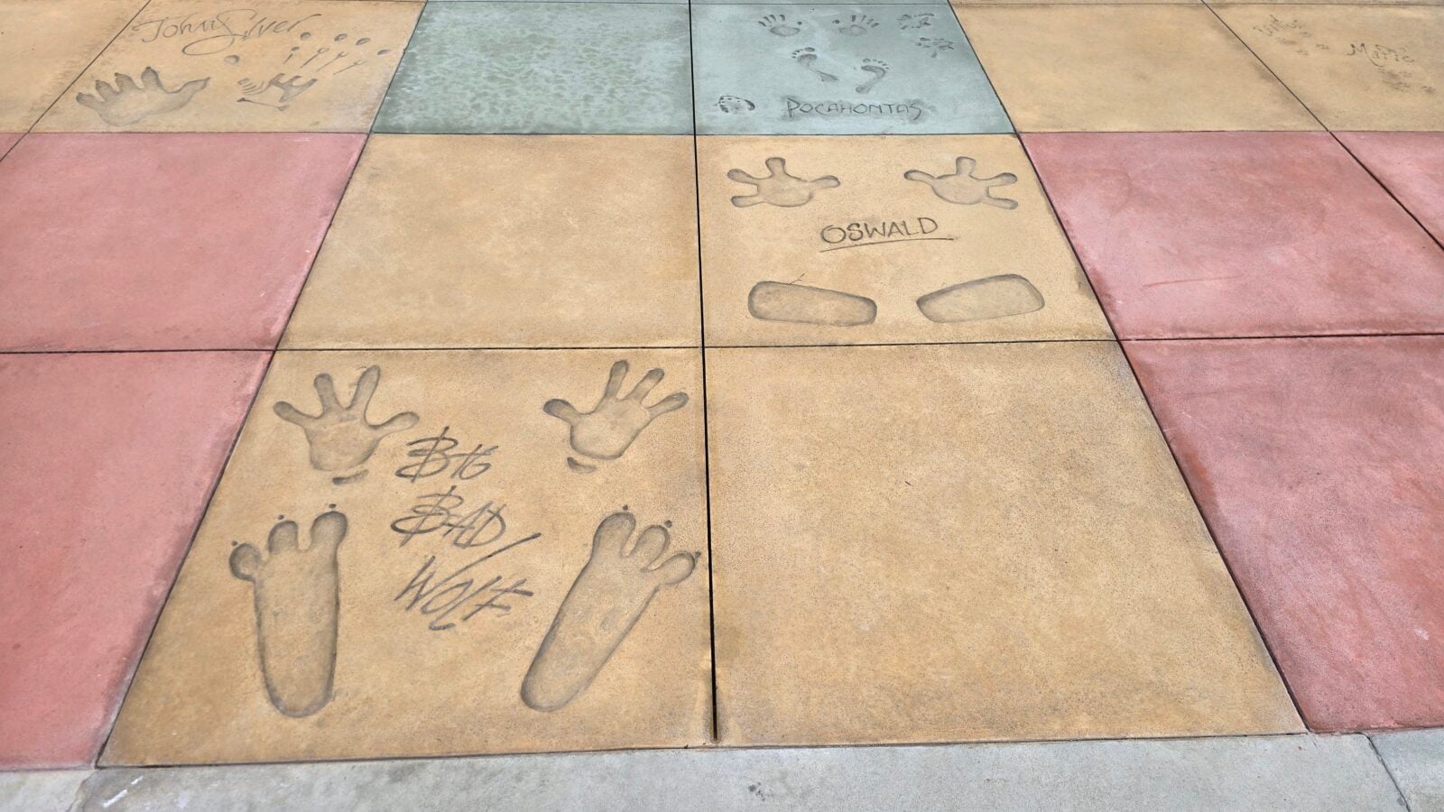 Colored concrete tiles with handprints and footprints pressed into the surface some names visible on the slabs