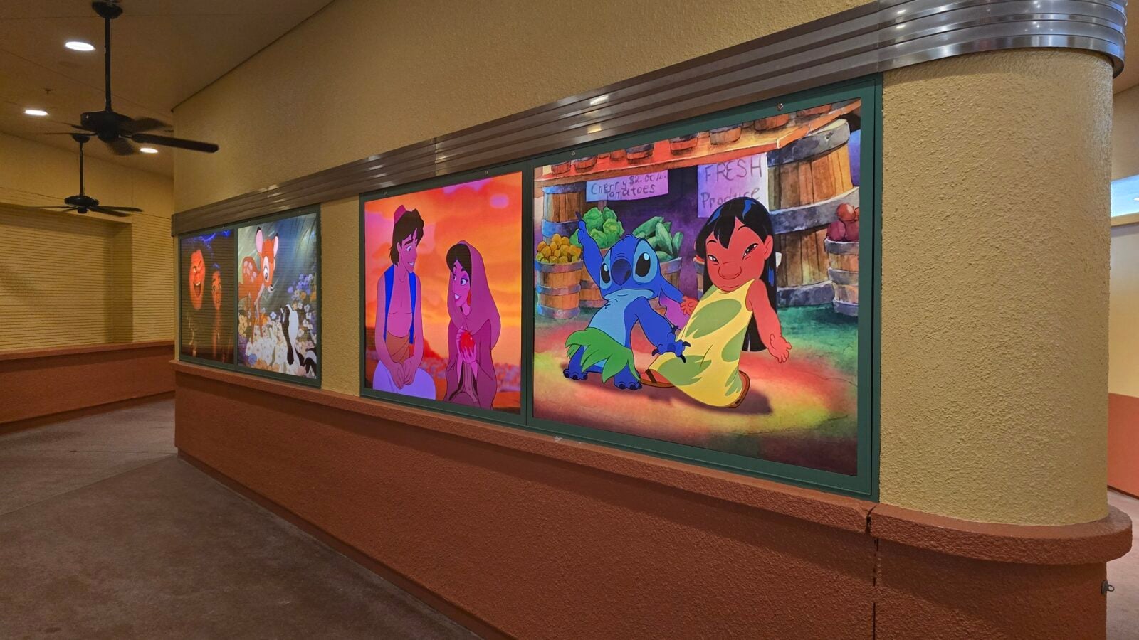 Interior hallway with large colorful cartoon panelslikely scenes from Disneys Lilo  Stitchmounted along a green trimmed wall