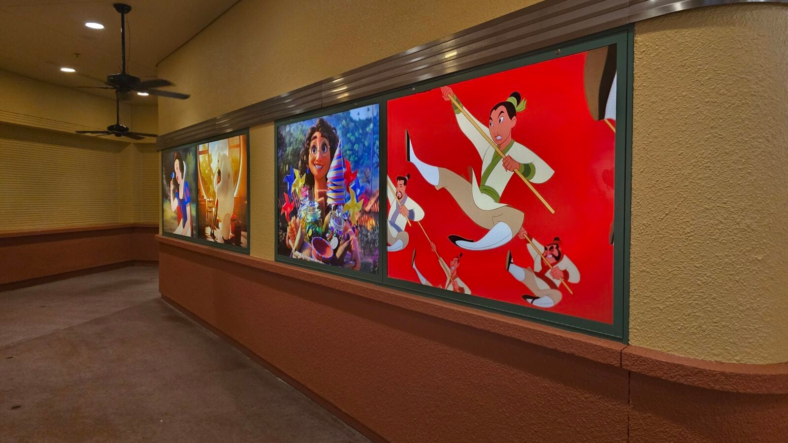 A long corridor with four large brightly colored framed posters of cartoon characters along the wall