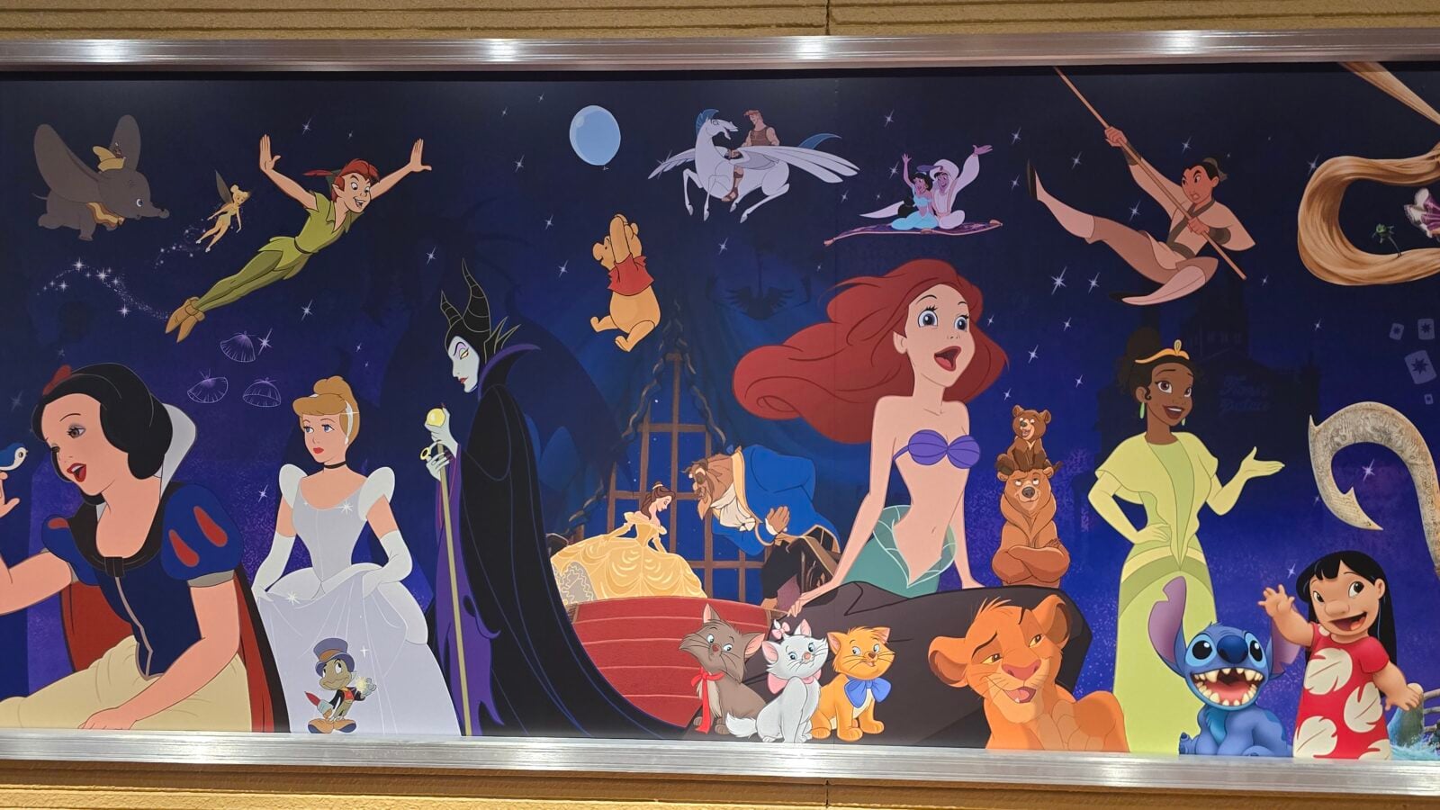 Colorful wall mural showing multiple Disney princesses and mascots in a night sky scene filled with stars and animals