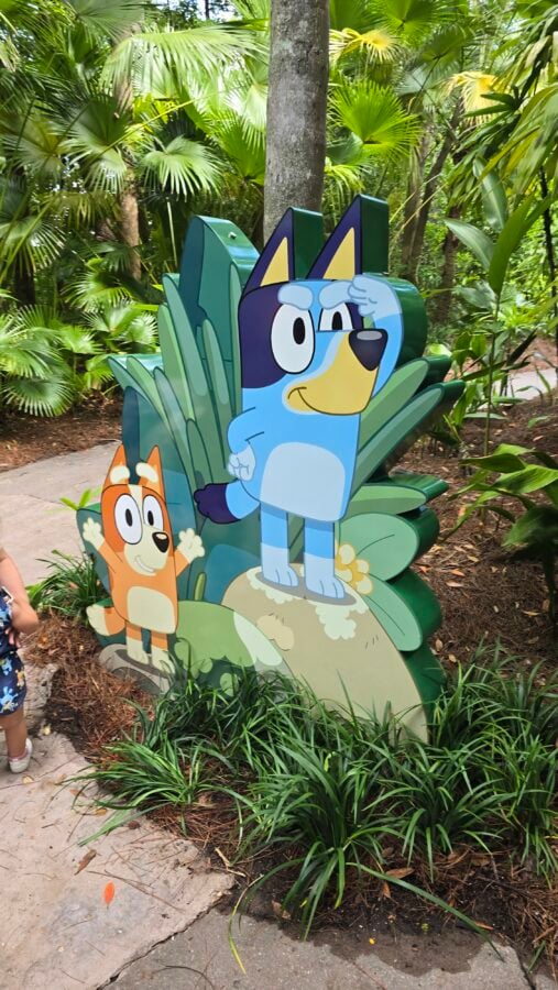 20260525104911 Fantasy Land News Colorful cartoon dog cutouts in a lush tropical garden display