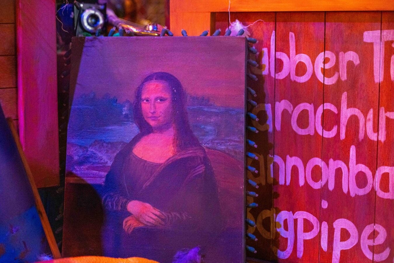 Mona Lisa replica propped against a colorful neon lit wooden wall in an art installation setting