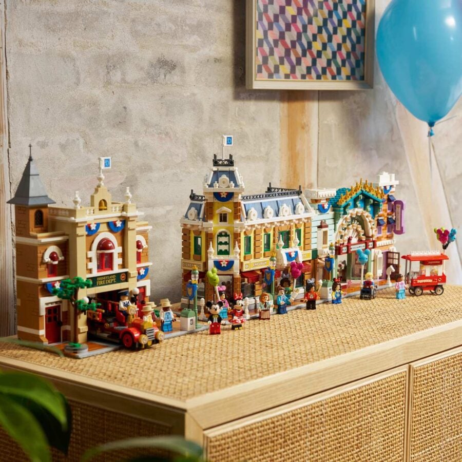 A detailed LEGO city display on a wooden shelf with buildings minifigures and a blue balloon nearby