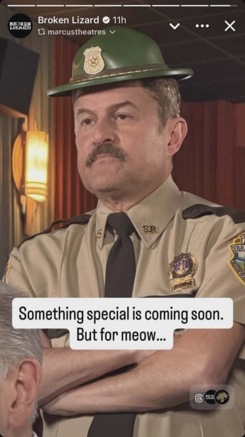 Male police officer in a tan uniform and black tie wearing a green helmet with badge standing with arms crossed indoors caption text on screen says Something special is coming soon But for meow