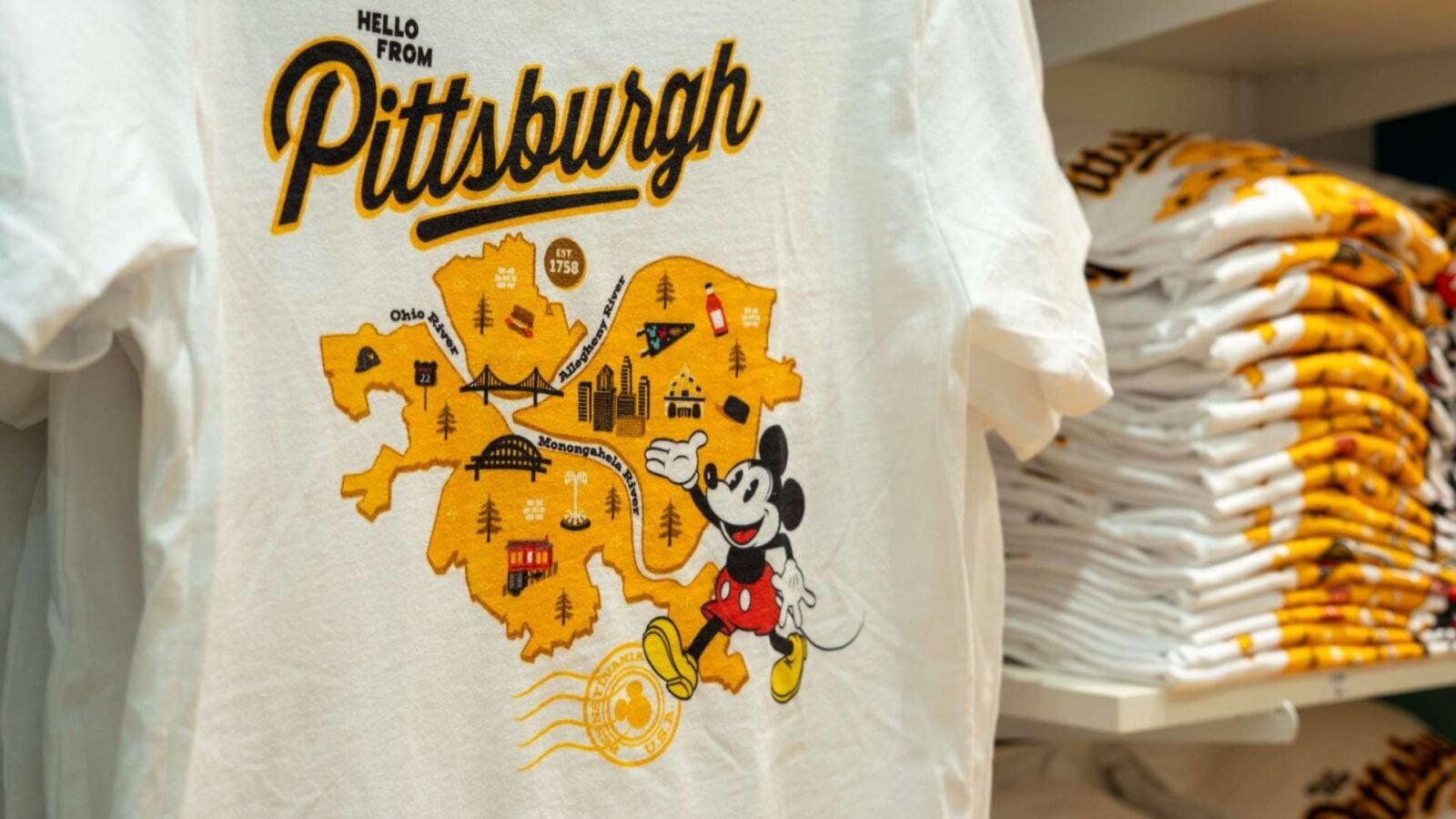 Disney Store Limited Time Opens Tomorrow at Ross Park Mall in Pittsburgh 1 Fantasy Land News White T shirt with a yellow Pittsburgh map graphic and Mickey Mouse text says Hello from Pittsburgh on a store display backdrop