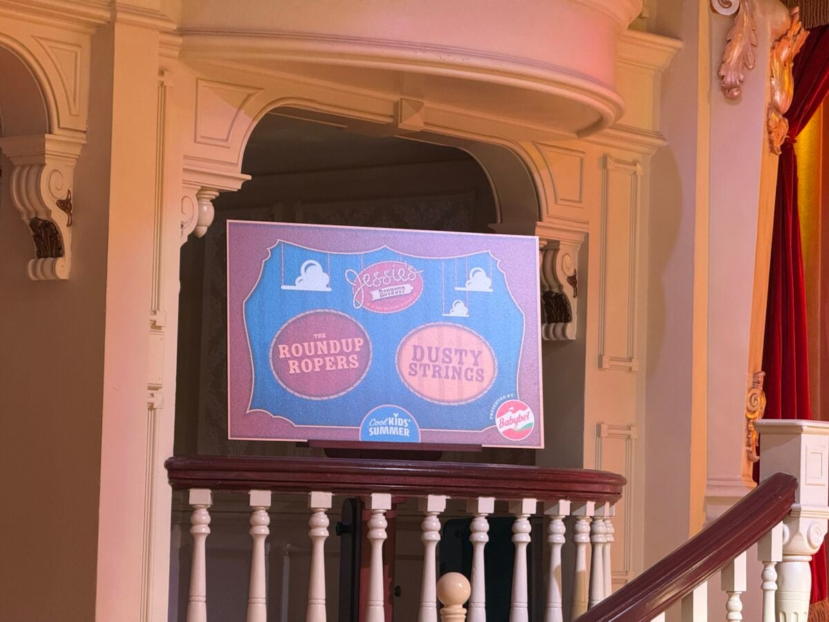 Ornate theater balcony with decorative plasterwork and a blue poster showing circular logos for a western show like The Roundup Ropers and Dusty Strings