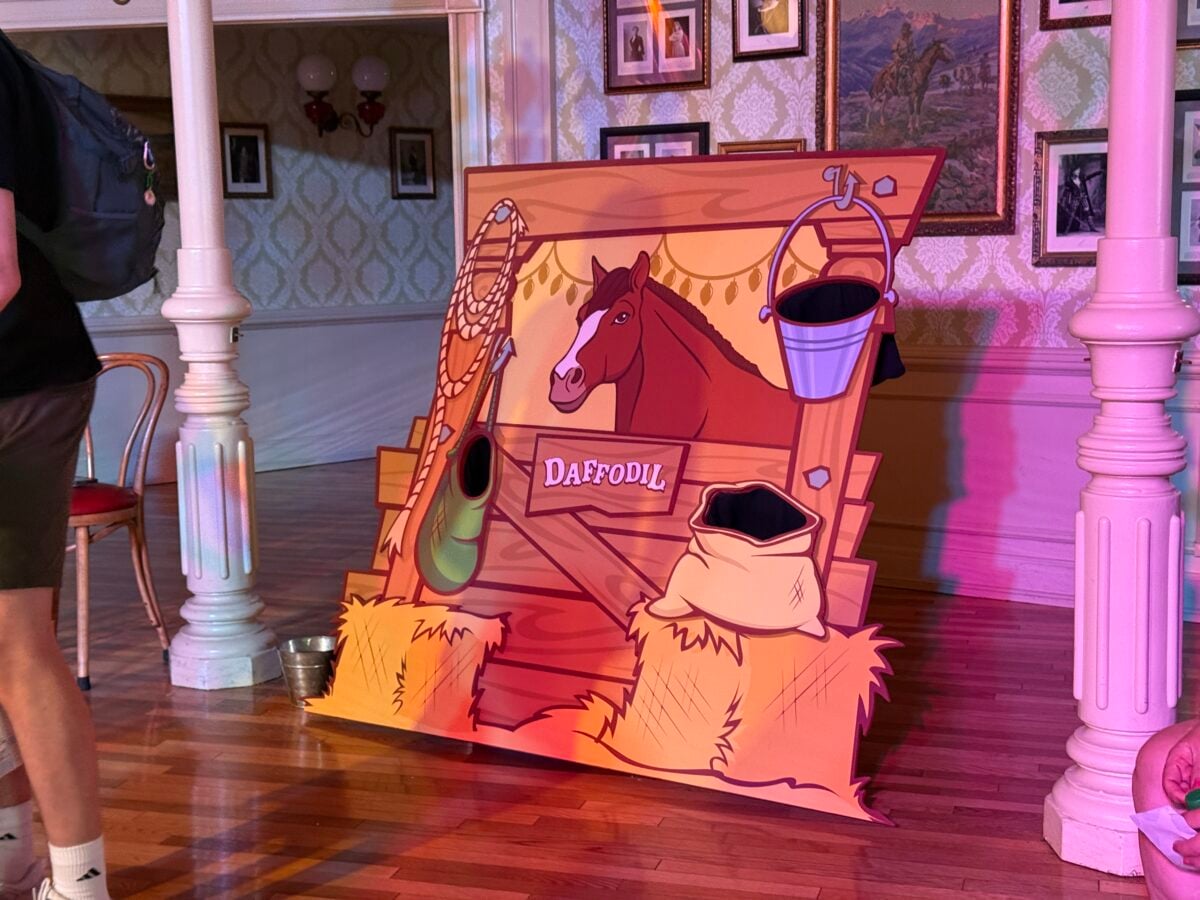 Colorful cartoon horse prop with a rope and bucket labeled Daffodil set in a vintage style room with wallpaper and columns photo backdrop