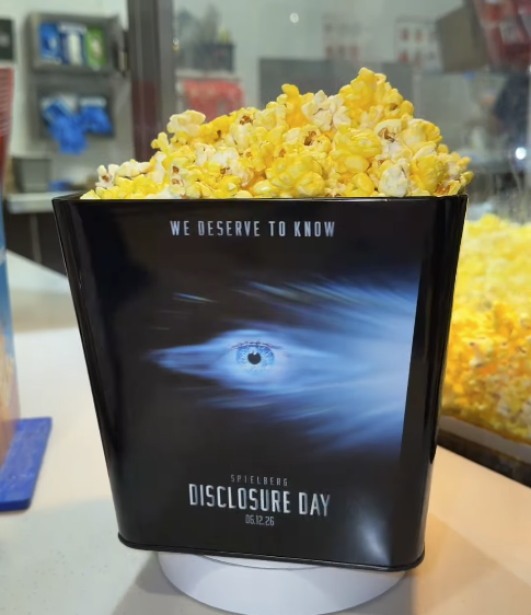 Screenshot 20260527 080820 Fantasy Land News Popcorn bucket on a counter with a poster for Disclosure Day and the tagline We deserve to know