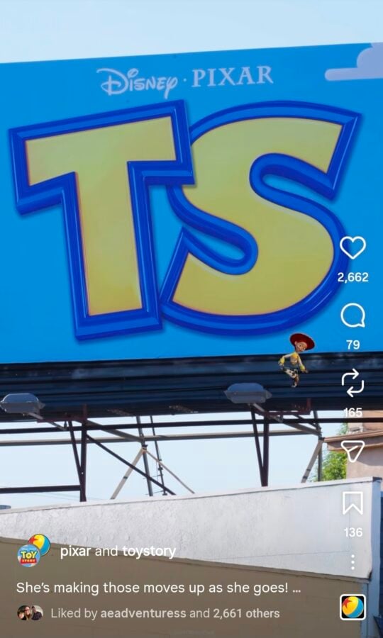 Bright blue billboard with oversized yellow letters outlined in blue reading TS Disney Pixar logo above Toy Story branding at bottom left