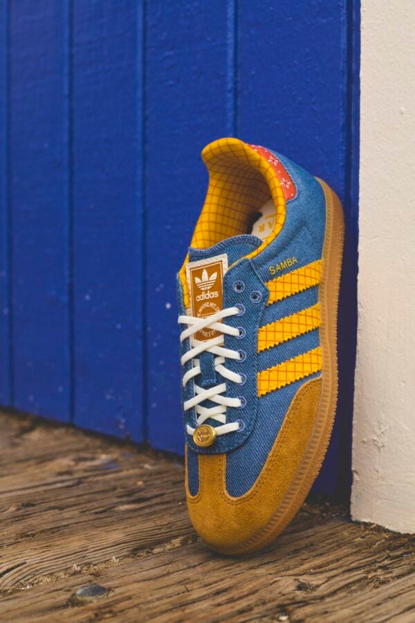 adidas x Toy Story 6 Fantasy Land News Blue and yellow Adidas Samba sneaker resting against a blue wall with a wooden floor visible at the bottom