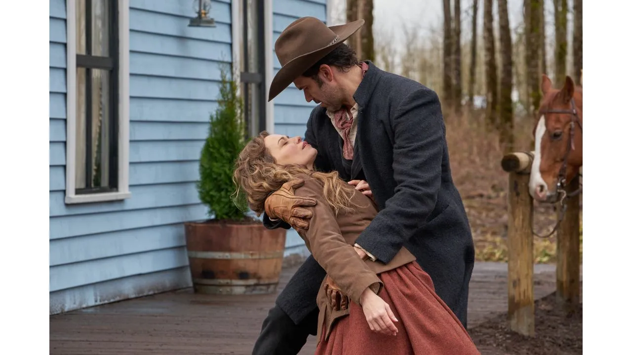 Man in a brown hat hugs a woman on a wooden porch with blue siding and a horse in the background