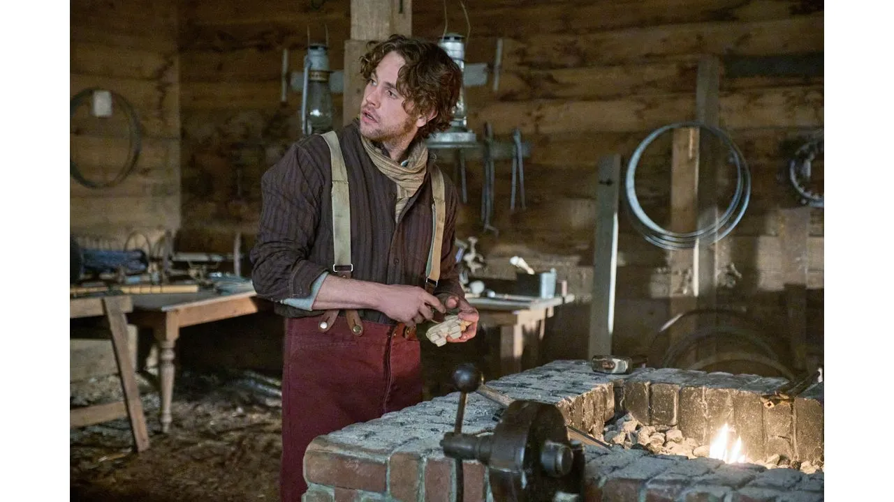 Blacksmith in a rustic workshop standing by a brick forge and holding a hot metal piece with tongs