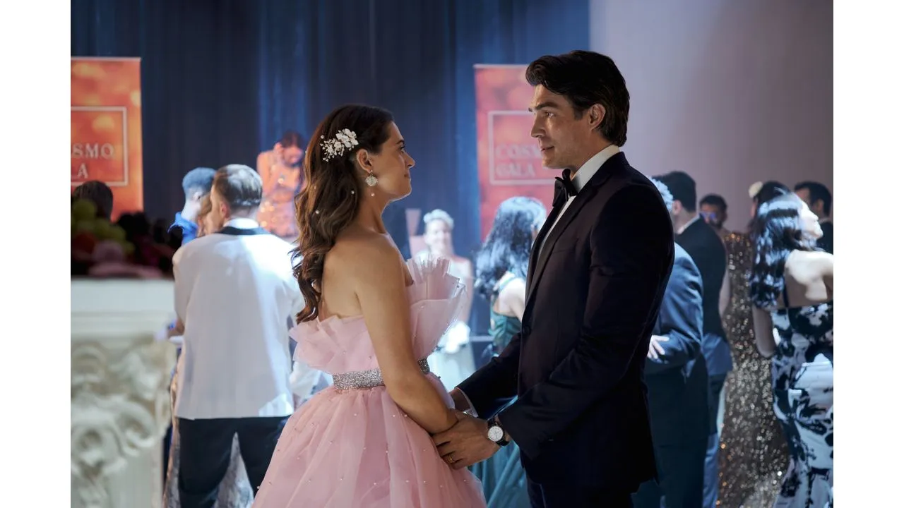 june4 Fantasy Land News Couple dancing at a formal event woman in a pink strapless gown and man in a black suit holding hands on a dance floor with guests in elegant attire in the background