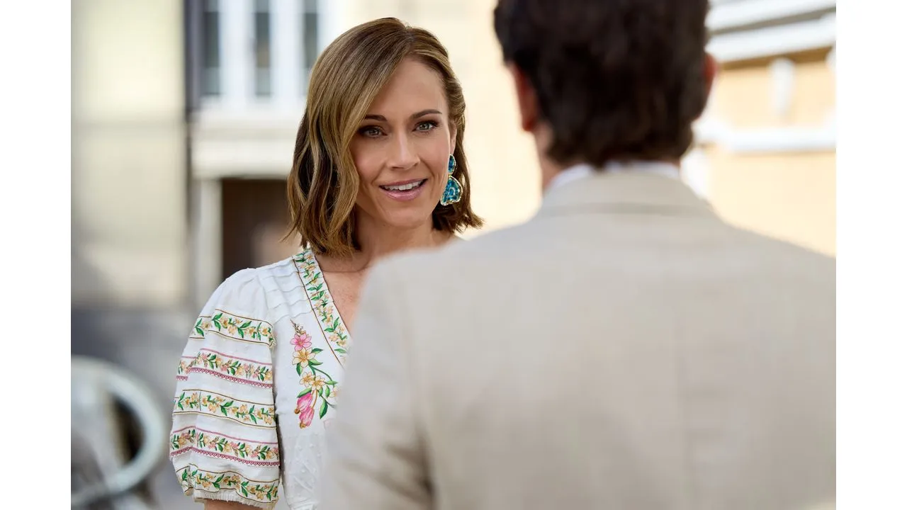 june7 Fantasy Land News Woman facing a man smiling wearing a white floral blouse and turquoise earrings outdoors