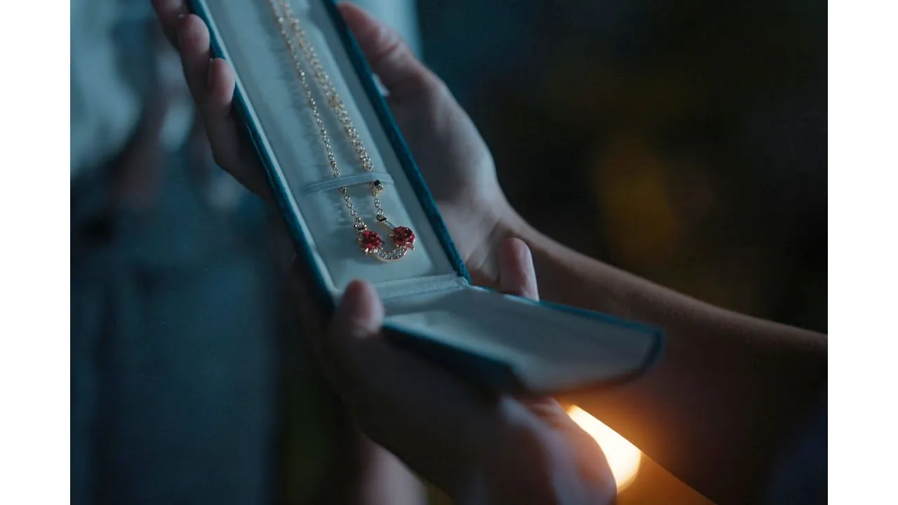 Open blue jewelry box revealing a pendant necklace with red gems in the box