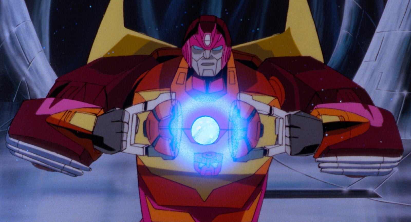transformersstill02 Fantasy Land News Autobot in pink and orange armor holds a glowing blue EnergonMatrix orb with both hands in a dramatic stance