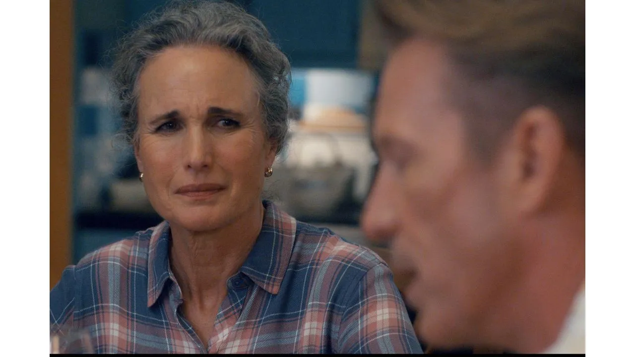 Older woman with gray hair wearing a blue and red plaid shirt looks concerned while talking to a man off camera