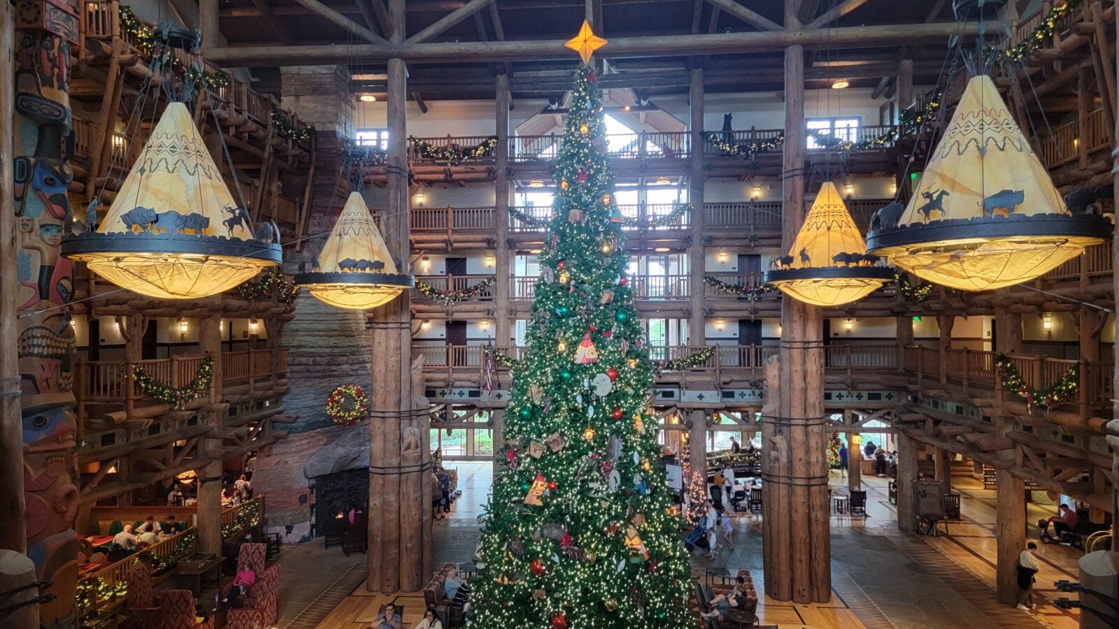 20231126124048 Fantasy Land News Indoor lodge atrium with a tall Christmas tree string lights and large hanging lantern like tents sculpted with horses and bison motifs Camille style