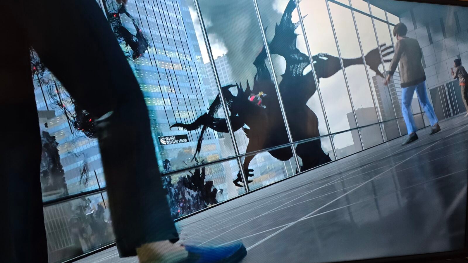 Two people walk along a glass walled corridor as a large black dragon mural is reflected in the windows