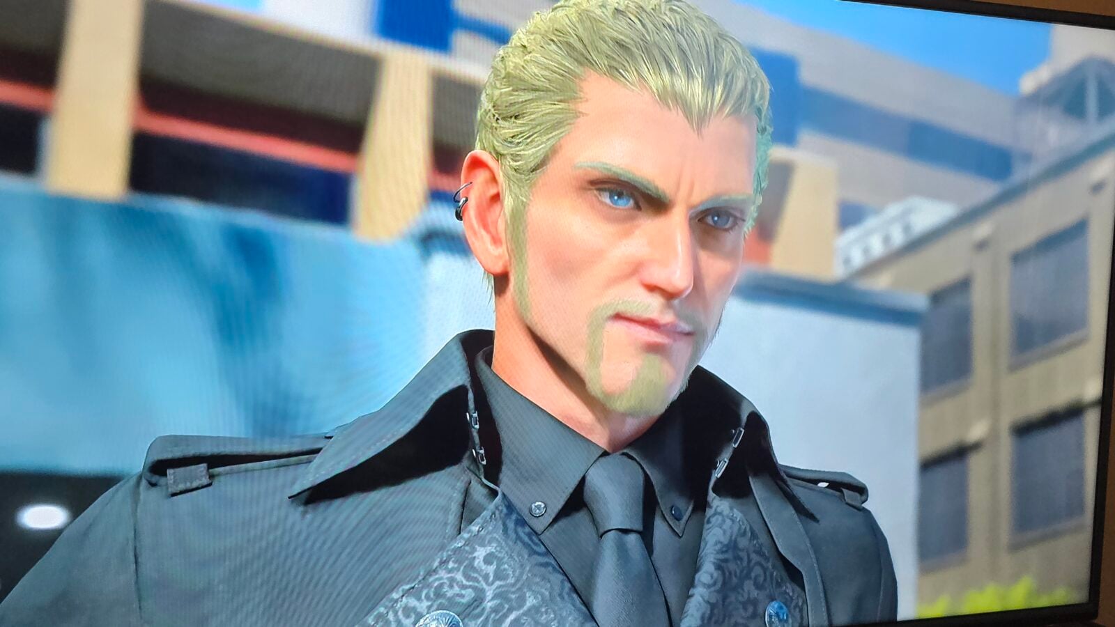 Close up of a man with mint green hair and blue eyes wearing a gray uniform with a patterned vest and looking to the side