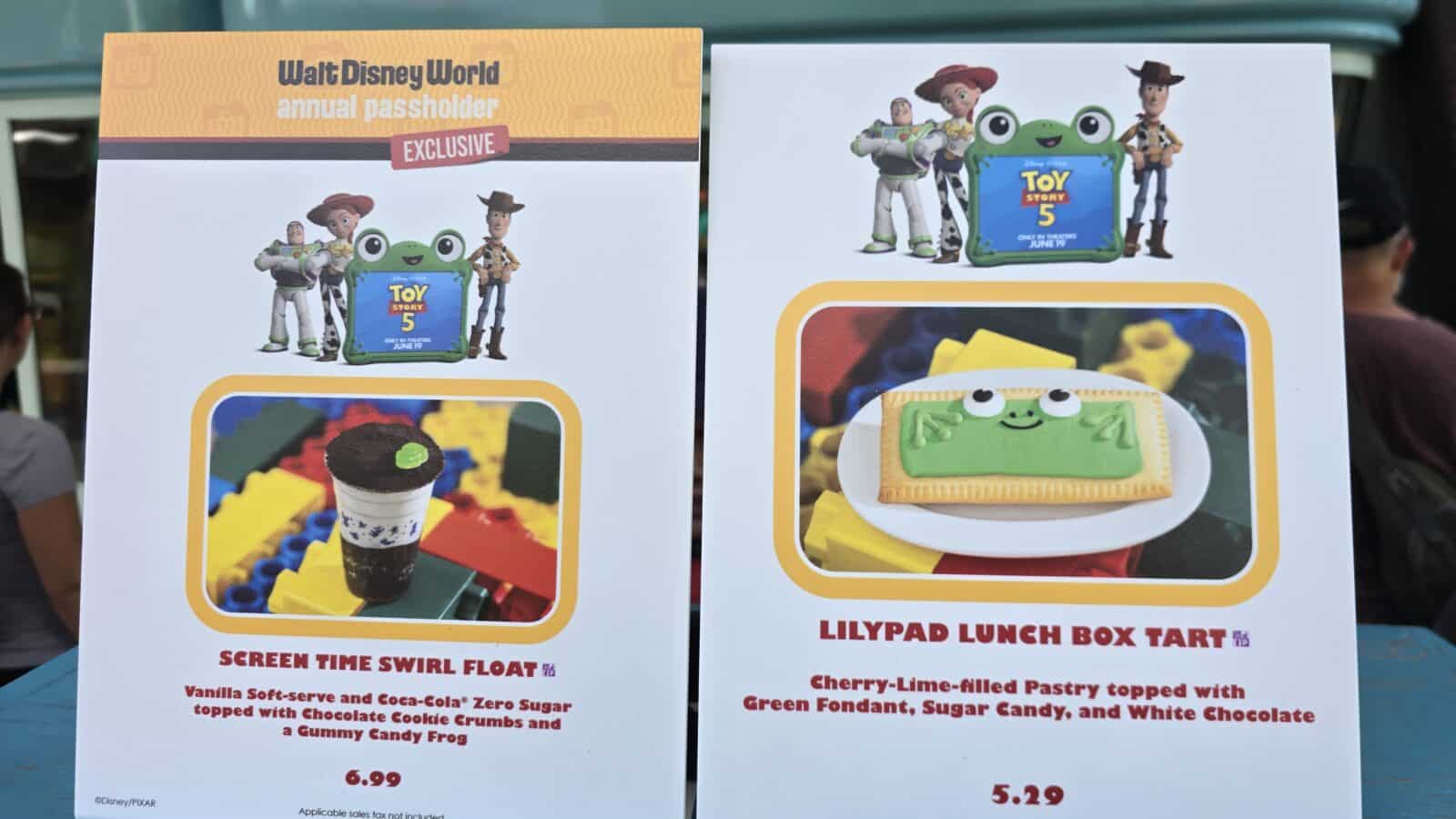 Two Disney posters side by side advertising Toy Story snacks showing Woody and Buzz with a green frog lunch box