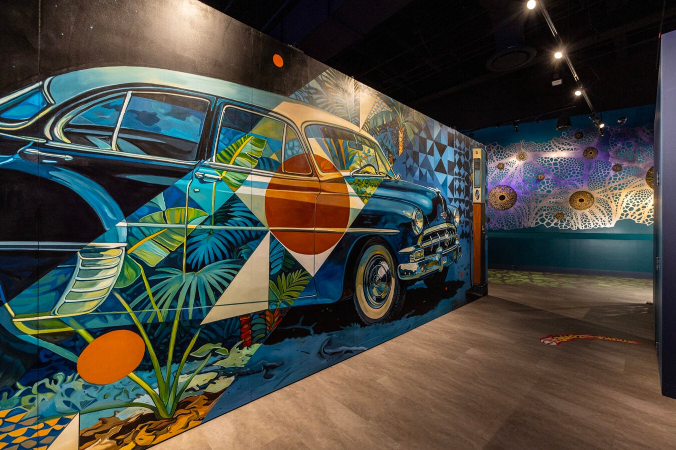 Vibrant mural of a vintage blue car with tropical leaves on a gallery wall colorful geometric backgrounds
