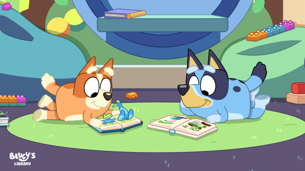 BlueysLibraryPreview01lg11024x576 Fantasy Land News Two cartoon puppies lie on a green rug and read animal picture books together in a bright playroom library of toys and colorful shapes