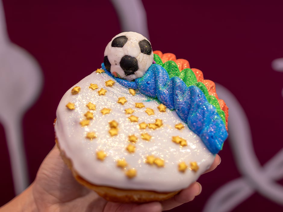 Cupcake with white icing gold star sprinkles and a soccer ball fondant topper next to rainbow frosting