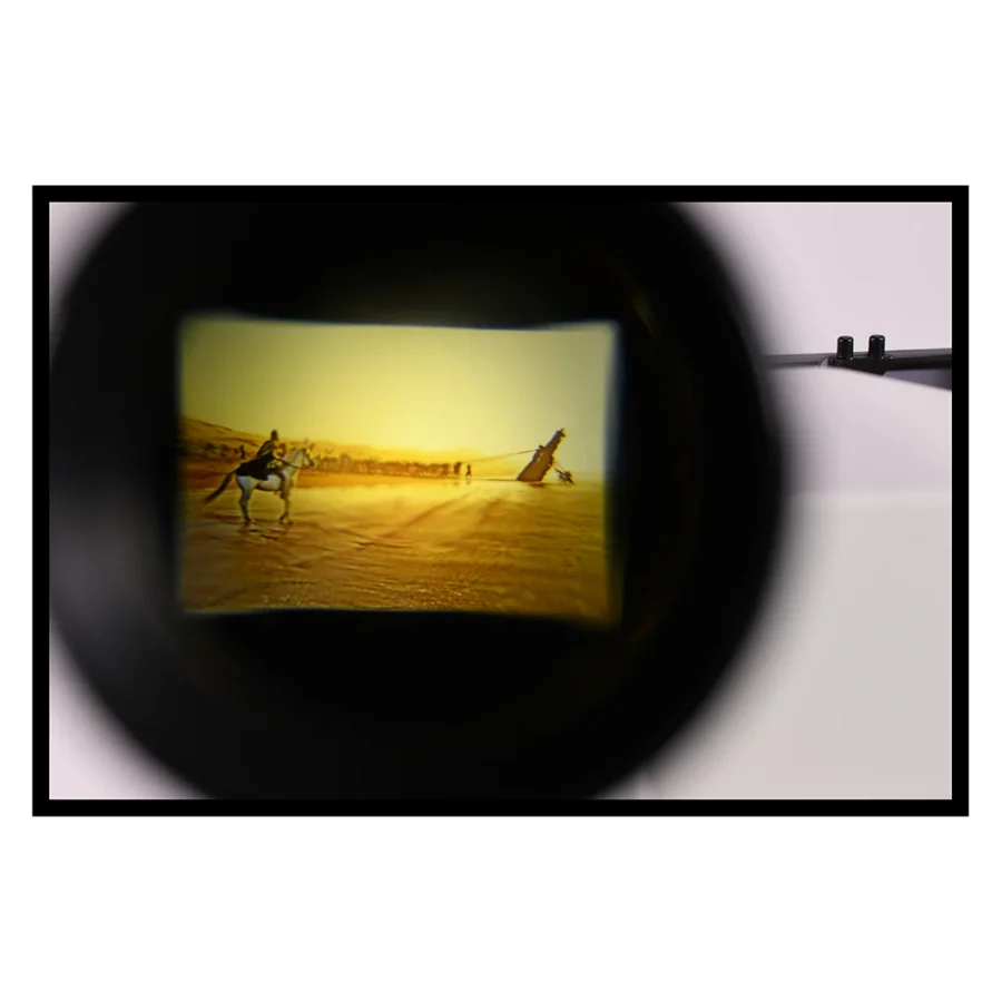 ImaxPB11781281579004 1 Fantasy Land News View through a camera lens showing a desert scene at sunset with two people on camels and a tilted object on the sand
