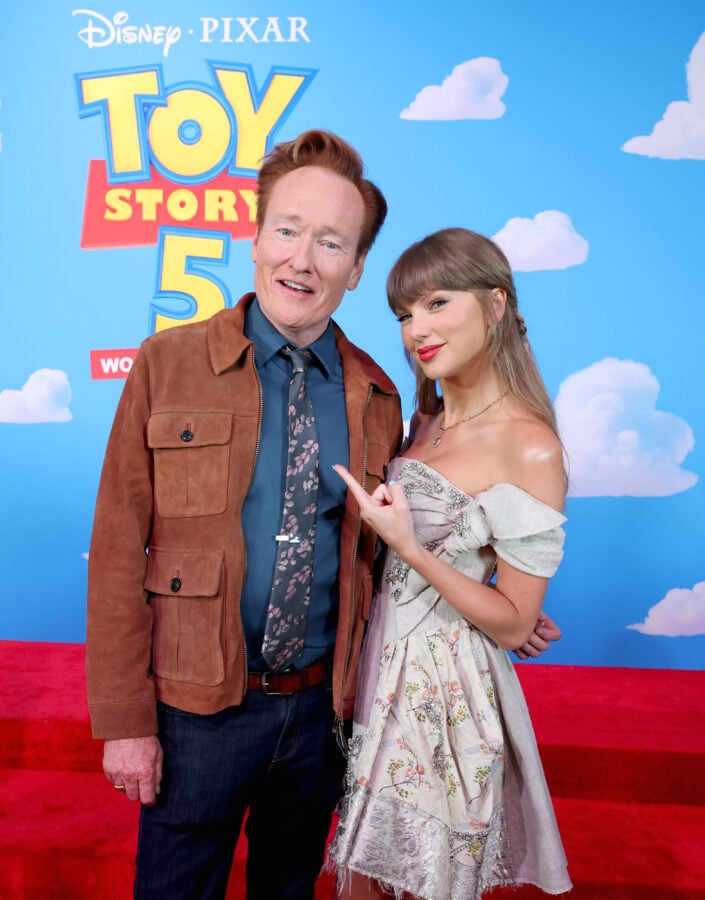 Toy Story 5 Los Angeles World Premiere Fantasy Land News Two celebrities pose together on a red carpet in front of a Toy Story 5 backdrop with a blue sky and clouds