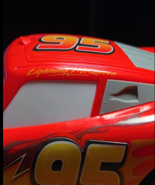 Red race car with a large 95 on the roof and Lightning McQueen script along the side A silver window panel and flame graphics are visible on the red body