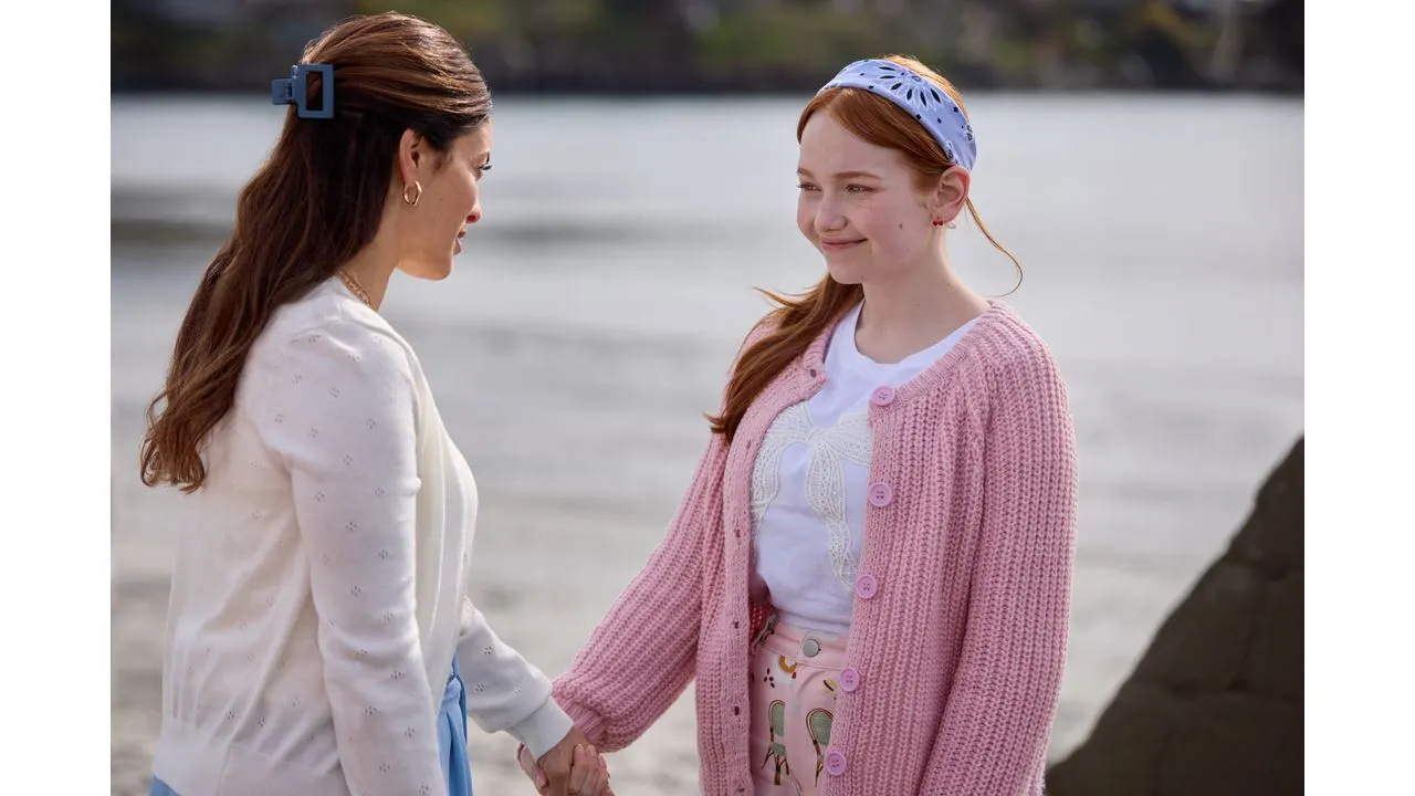 Two women by the water holding hands and smiling at each other enjoying a moment by the shoreline