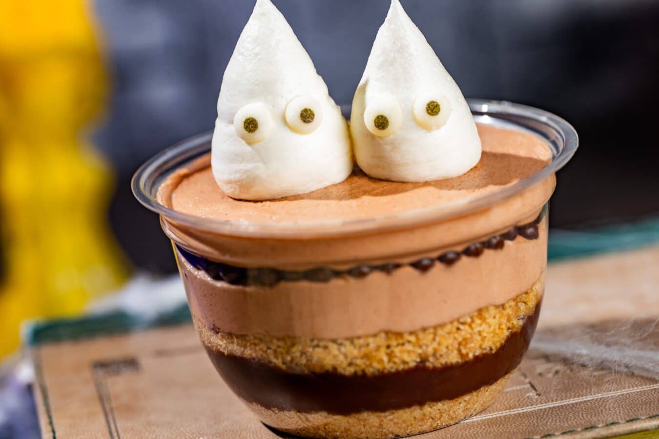 Chocolate mousse dessert in a cup topped with two white ghost shaped meringues with small candy eyes