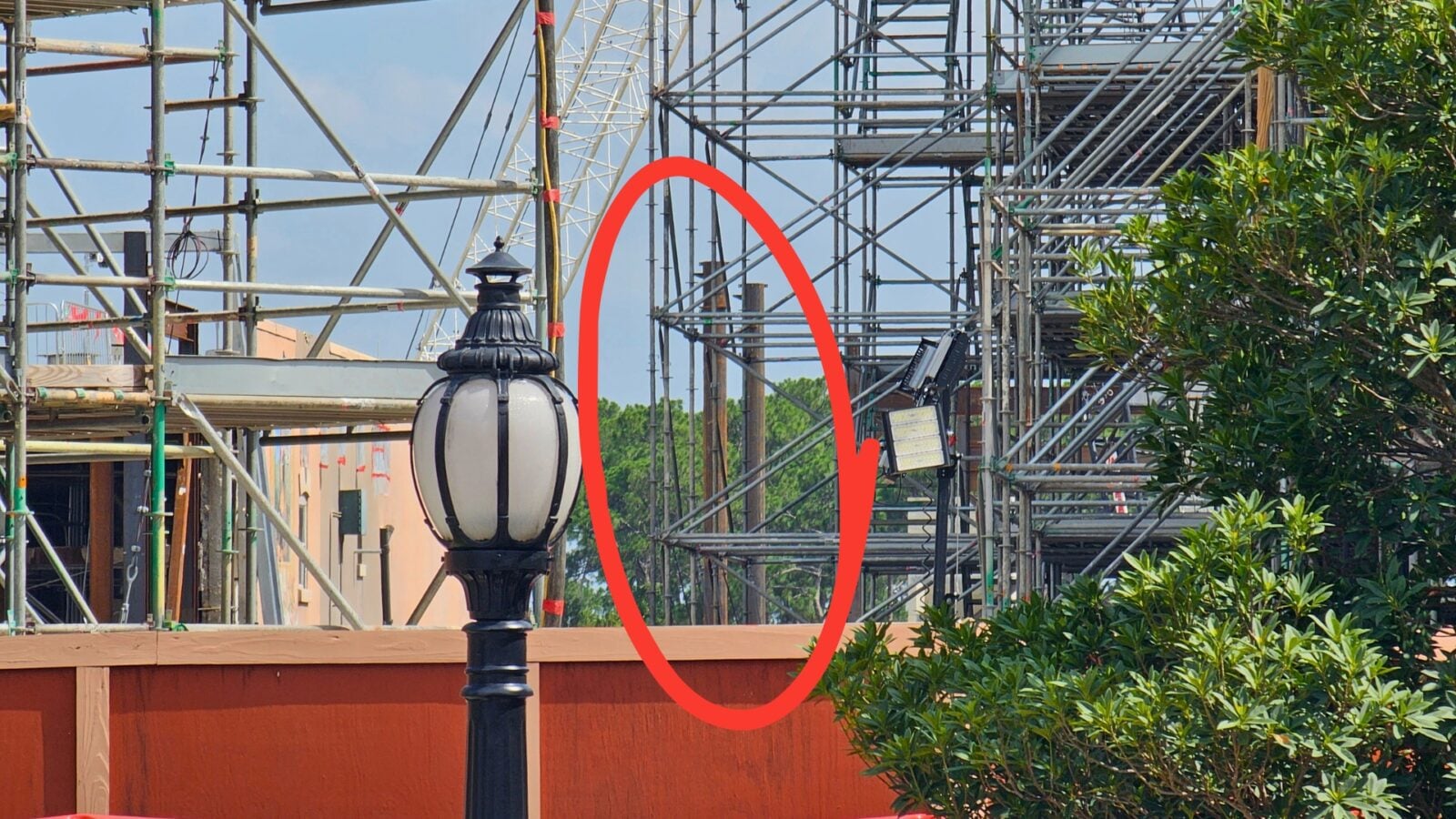 Decorative street lamp in the foreground with complex metal scaffolding behind a construction site circled area highlighting a vertical post