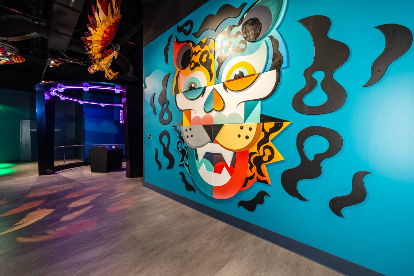 Vibrant abstract mural on a bright turquoise wall inside an art gallery