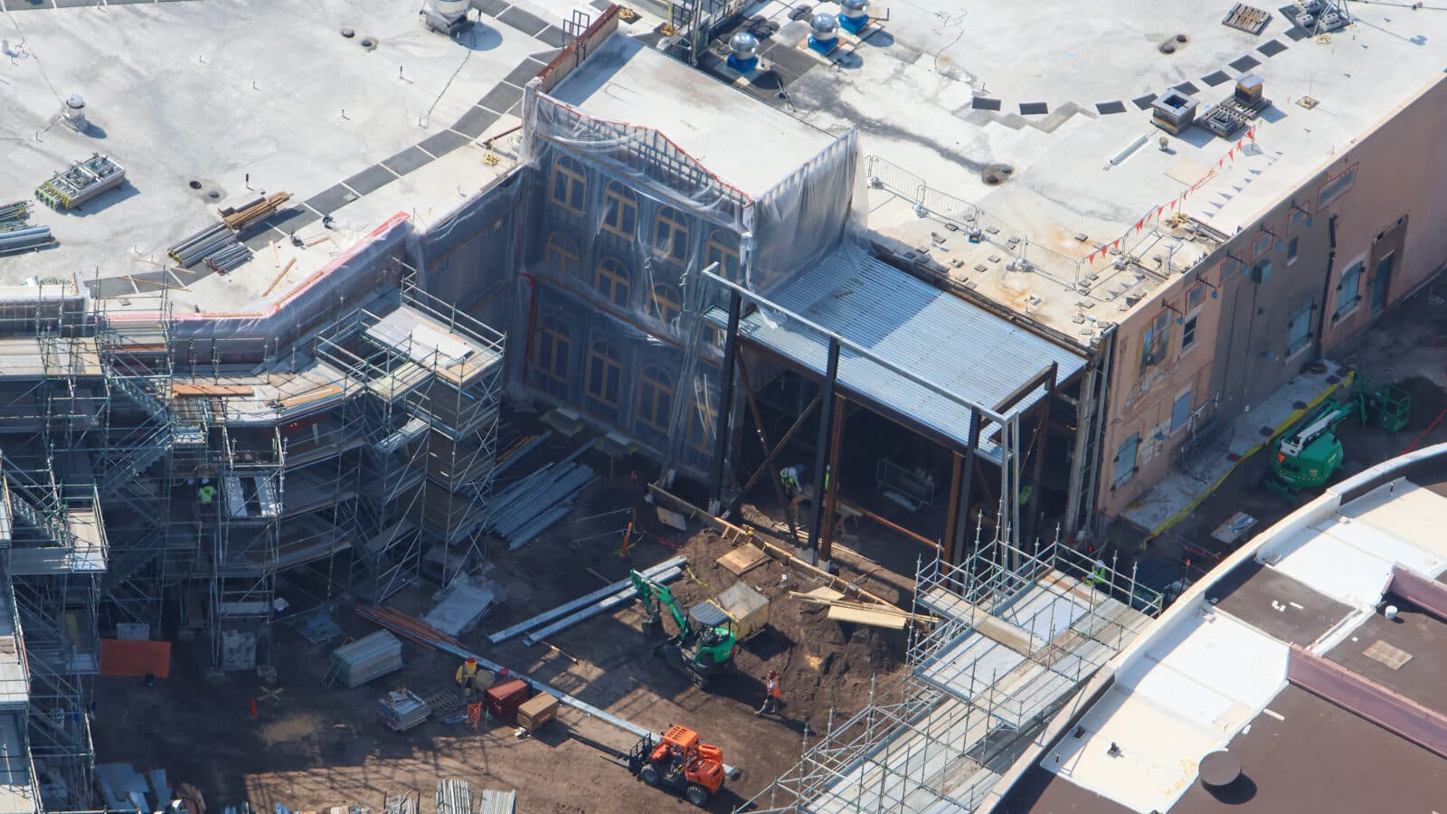 Aerial view of a construction site with scaffolding around a multi story partially enclosed building under renovation