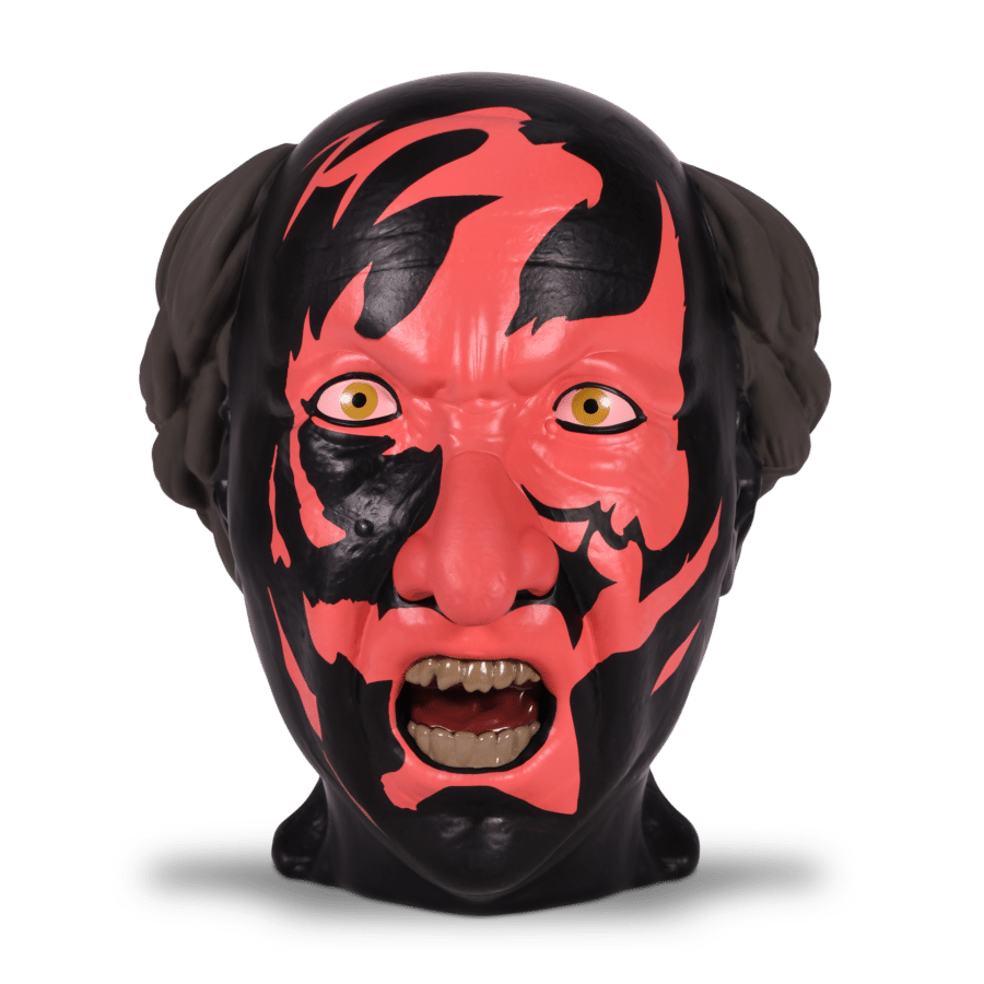 Close up of a red and black demon mask with yellow eyes and an open mouth against a black background