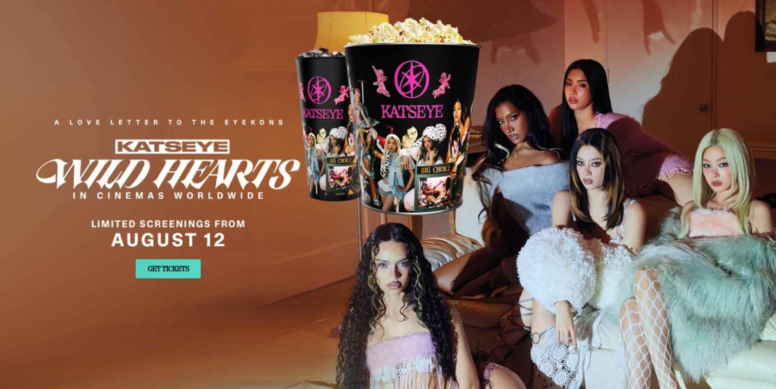 Promotional banner for KatEyes Wild Hearts with oversized popcorn cups and a group of stylish women posing in a living room setting